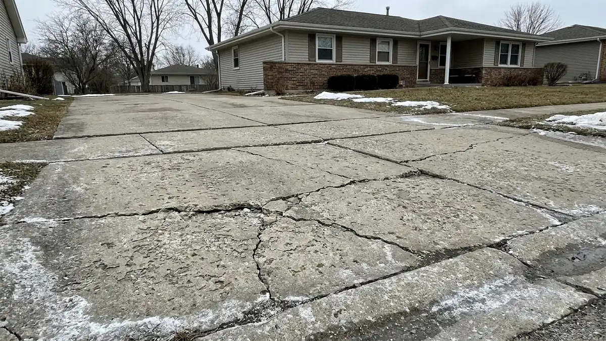 Freeze-thaw damaged concrete driveway in Joliet Illinois Will County salt scaling cracking heaving deicing damage spring